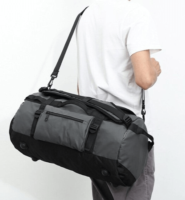 Person carrying a waterproof sports bag with separate compartments for dry and wet clothes, made of durable polyester.